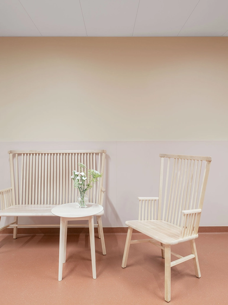 pinnsoffa och pinnstol med hög rygg samt ett litet bord i ljust trä, terrakottafärgad golv och ljusa väggar